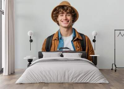 Young caucasian man over isolated background in vacation with travel suitcase and a hat Wall mural