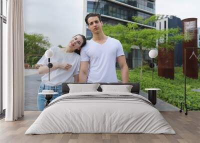 Stylish young couple is spending time together outdoors. Attractive woman and handsome man are posing in the street Wall mural