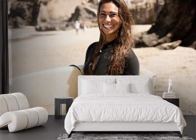 girl standing on the beach holding a surfboard Wall mural