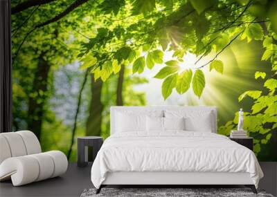 A picturesque forest of young, green deciduous trees is framed by leaves, and the light is shining warmly through the treetops. Generative AI Wall mural