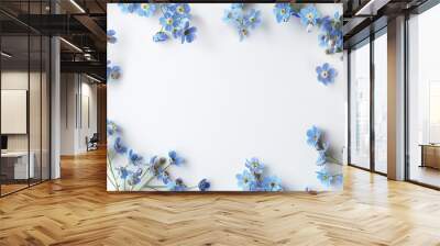 A top down view of delicate blue forget me not flowers set against a crisp white backdrop providing a blank canvas for your text Wall mural