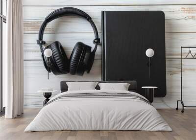 Black book and headphones on white wooden background for audio book concept Wall mural