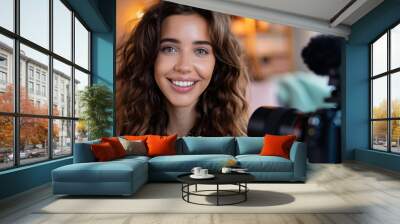 Smiling vlogger woman posts selfie on social media for online content. Influencer records podcast vlog with professional equipment. Wall mural