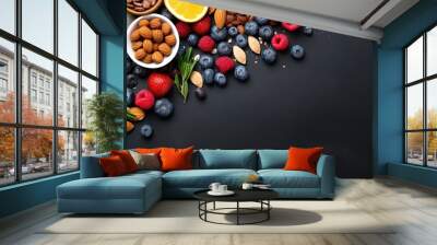 Top view of seasonal natural organic breakfast ingredients nuts oatmeal honey berries fruits like blueberry orange and pomegranate seeds almonds and walnuts with copyspace for text Wall mural