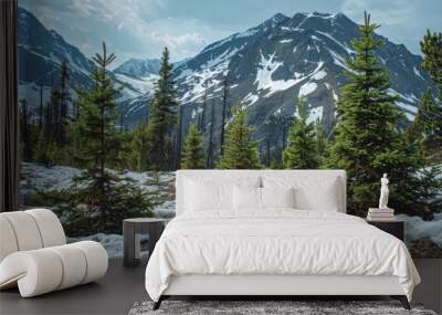 Young evergreen trees thrive on the rugged mountainside amid snowy peaks during the spring Wall mural