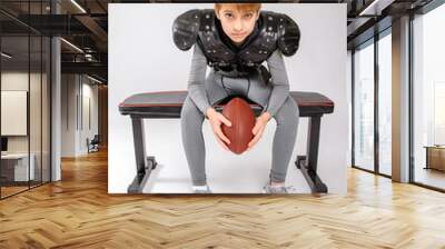 Preteen football sports boy sitting on bench in studio with white background wearing football pads compression clothing Wall mural