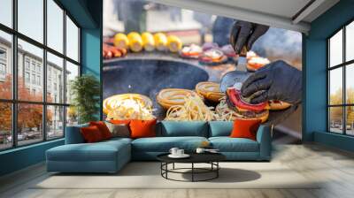 A person wearing black gloves is preparing hamburgers. In the background is a grill where the burgers are being cooked. A close-up of the grill, showing the final stages of assembling the burgers. Wall mural