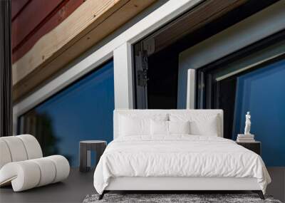 Close-up of a white window frame with a metal hinge and a chain mechanism. The window is open, revealing a view of blue sky. The image captures the details of the window's construction. Wall mural