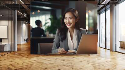 Portrait of happy asian businesswoman working on laptop in cafe Wall mural