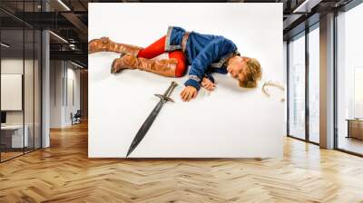 Young boy dressed up like a cosplay prince lying on the ground defeated in battle Wall mural