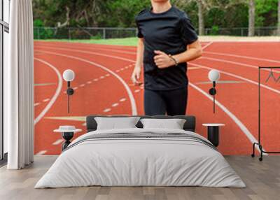 Young male track athlete running in his lane during a race Wall mural