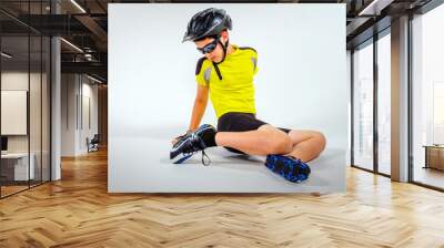 Young preteen boy model cyclist sitting on studio floor in biking uniform with white background Wall mural