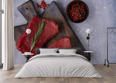 Two raw beef steak with spices and rosemary on table Wall mural