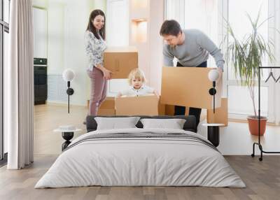 Happy young family with unpacking boxes at new home on moving day Wall mural