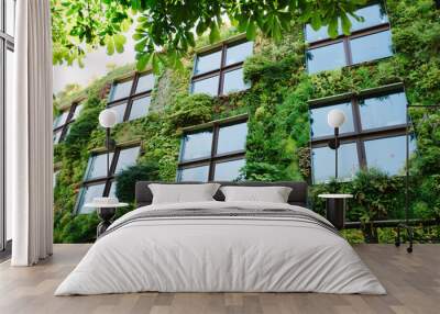 Green architecture concept. Building exterior covered with plants in modern city Wall mural