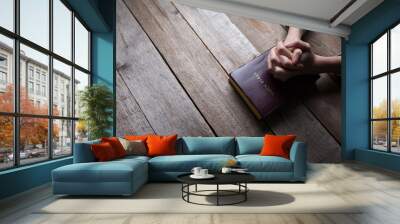 hands praying with a bible in a dark over wooden table Wall mural