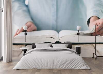 Hands turning the page of a bible. Woman reading a big book or a Bible Wall mural