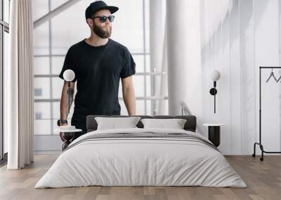 Hipster handsome male model with beard wearing black blank t-shirt with space for your logo or design in casual urban style Wall mural