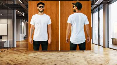 Hipster handsome male model with beard wearing white blank t-shirt and a baseball cap with space for your logo or design in casual urban style. Back and front view Wall mural