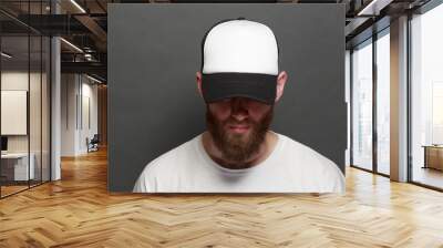 Hipster handsome male model with beard wearing white blank t-shirt and a baseball cap with space for your logo or design in casual urban style Wall mural