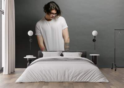 Hipster handsome male model with glasses wearing white blank t-shirt and black jeans with space for your logo or design in casual urban style Wall mural