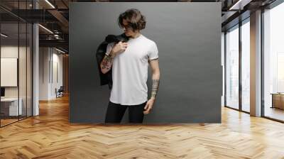 Hipster handsome male model with glasses wearing white blank t-shirt and black jeans with space for your logo or design in casual urban style Wall mural