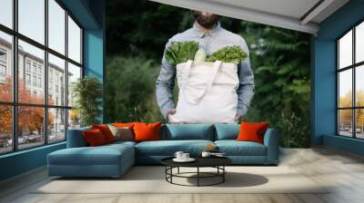 Man holding an eco bag filled with grocery. Vegetables and fruits. Ecology concept environment protection. Wall mural