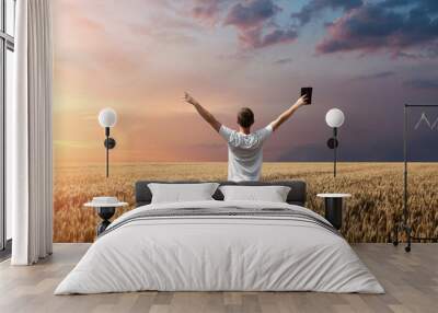 man holding up Bible in a wheat field Wall mural