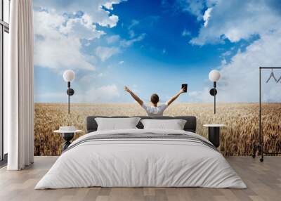 Man holding up Bible in a wheat field Wall mural