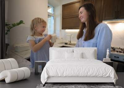 Mother and a small daughter cooking food at home in the kitchen Wall mural