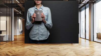 Woman holding a Bible in hands wearing casual clothes over gray backgound Wall mural