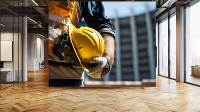 Construction worker holding his helmet and wearing fluorescent waistcoat while looking at construction site. Occupational Safety and Health (OSH)  Wall mural