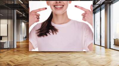 Cut view of young woman wear braces on her white teeth. Point on them with fingers and smile. Dental care. Straightening teeth. Beautiful smile. Young woman isolated. Wall mural