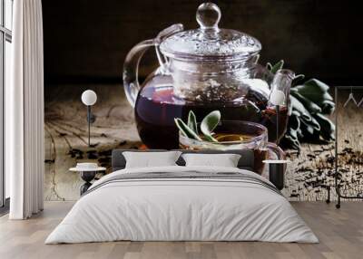 Black tea with fresh sage, glass cup and teapot, dark wood backg Wall mural