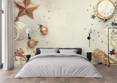 Christmas or New Year composition, frame, pink background with gold Christmas decorations, stars, snowflakes, balls, alarm clock, gift box and bottle of champagne, top view Wall mural