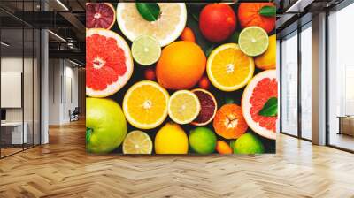 Colorful citrus fruis, food background, top view. Mix of different whole and sliced fruits: orange, grapefruit, lemon, lime and other with leaves on  green stone table Wall mural