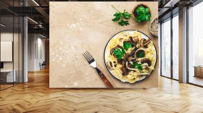 Cooked pasta with mushrooms with parsley on plate on beige stone kitchen table background, top view. Vegan cooking and eating, italian cuisine recipe Wall mural