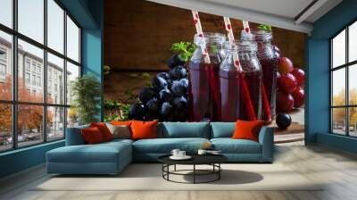 Dark grape juice in glass bottles with straws, blue grapes, dark Wall mural