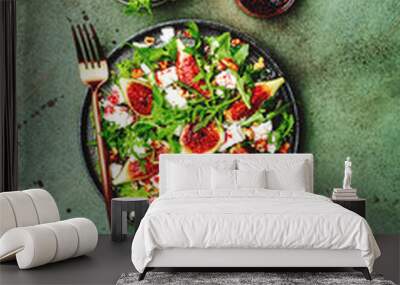 Delicious summer salad with figs, feta cheese, walnuts, arugula and sweet  jam dressing on rusty green table background, top view, negative space Wall mural