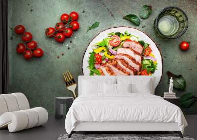 Duck salad with grilled breast and vegetables: red tomato, cucumber, paprika, onoin  and chard, frisse, mizuna and arugula leaves on green table background, top view Wall mural