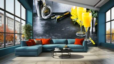 Festive alcohol cocktail mimosa with orange juice and cold dry champagne or sparkling wine in glasses, gray bar counter background with flowers, place for text, selective focus Wall mural