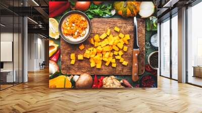 Food background. Diced raw peeled pumpkin and vegetable knife on rustic wooden cutting board. Vegetables, mushrooms, roots, spices - ingredients for vegan cooking. Healthy eating, comfort slow food  Wall mural