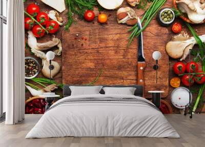 Food cooking background, ingredients for preparation vegan dishes, vegetables, roots, spices, mushrooms and herbs. Cutting board, chef knife. Healthy food concept. Rustic wooden table, top view Wall mural