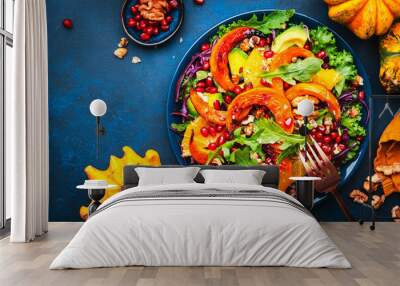 Fresh pumpkin salad with lettuce,  red cabbage, avocado, arugula, pomegranate seeds and nuts. Healthy vegan vegetarian eating, slow comfort food. Blue table background. Top view Wall mural