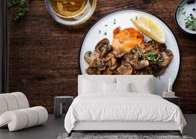 Fried chicken breast fillet with champignon mushrooms and onion in white wine sauce with thyme on plate, rustic wooden table background, top view Wall mural