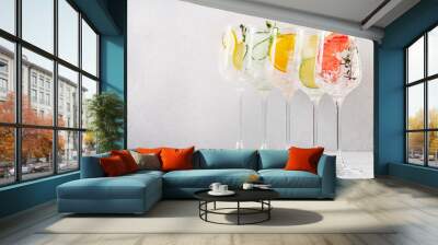 Gin and tonic cocktails set. Trendy Alcoholic drinks with lime, lemon, grapefruit, orange, cucumber, soda and spicy herbs in wine glasses, gray background. Summer cocktail party Wall mural