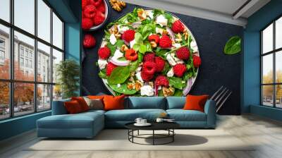 Gourmet salad with fresh raspberries, soft goat cheese, red onion, nuts, spinach and mixed herbs, black table background, top view Wall mural