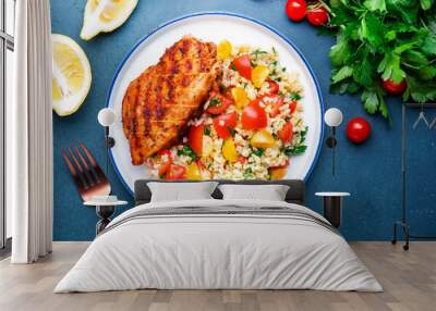 Grilled chicken with bulgur tabbouleh salad with tomatoes, parsley and olive oil and lemon dressing, blue stone table background, top view Wall mural