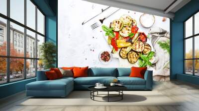 Grilled colorful vegetables, aubergines, zucchini, pepper with spice and green basil on serving board on white background, top view Wall mural