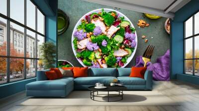 Healthy food salad with cauliflower, broccoli, chicken, cucumber, onion, radicchio, spinach with walnuts, green background, top view Wall mural